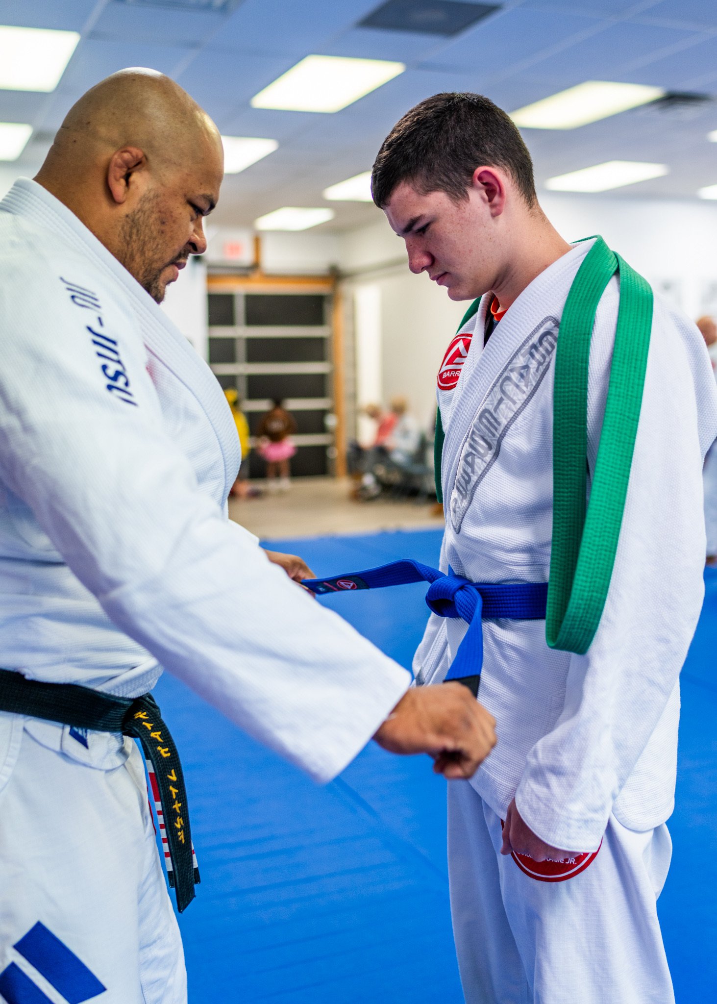 Professor Thiago Reinaldo promoting a student and adjusting his new belt at Gracie Barra Stafford