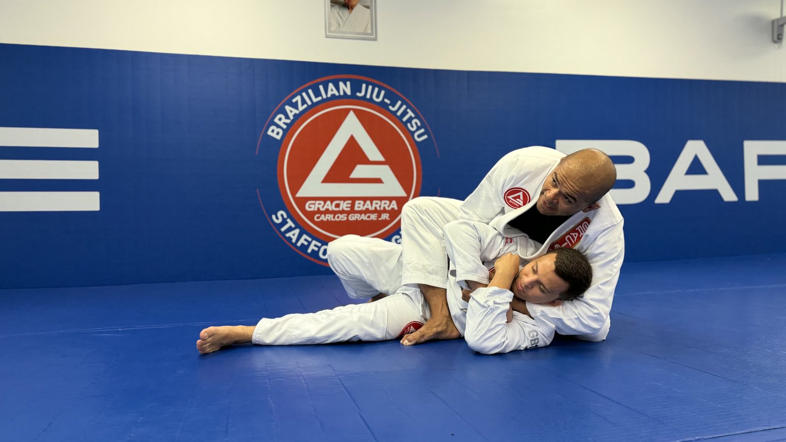 Thiago Reinaldo explaining a Brazilian Jiu Jitsu technique in front of the Gracie Barra Stafford identity
